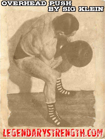 Sig Klein curling Cry dumbbell using two hands to push it overhead. 